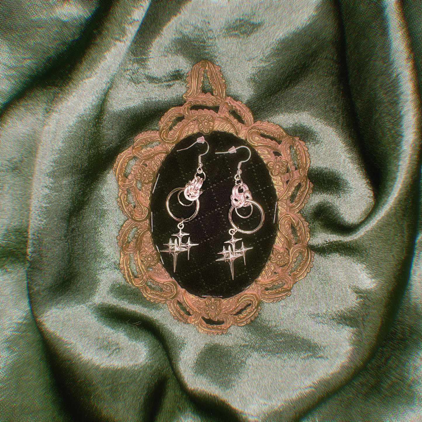 Pair of earrings on a decorative stand with green fabric background