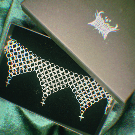 Silver chainmaille necklace in a black box with a brand logo in the background