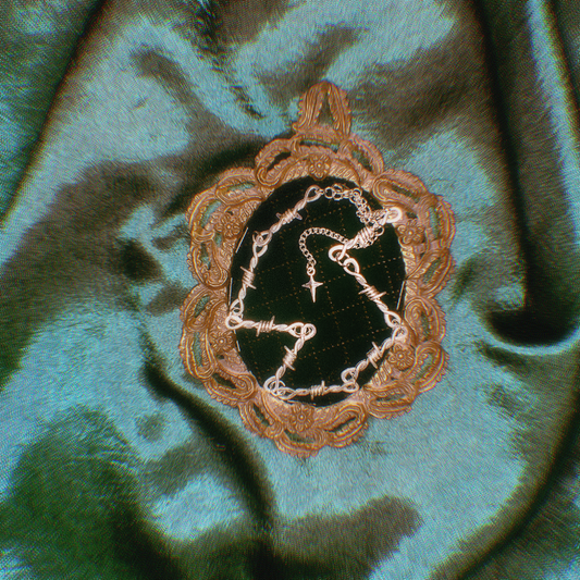 Barbed wire, silver necklace on a green fabric background