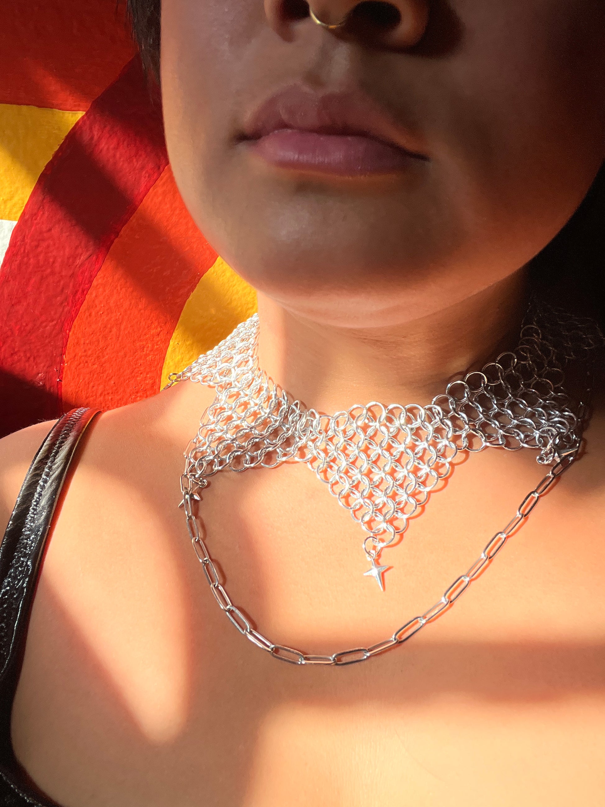 Close-up of a person wearing a chainmail necklace in dappled sunlight.
